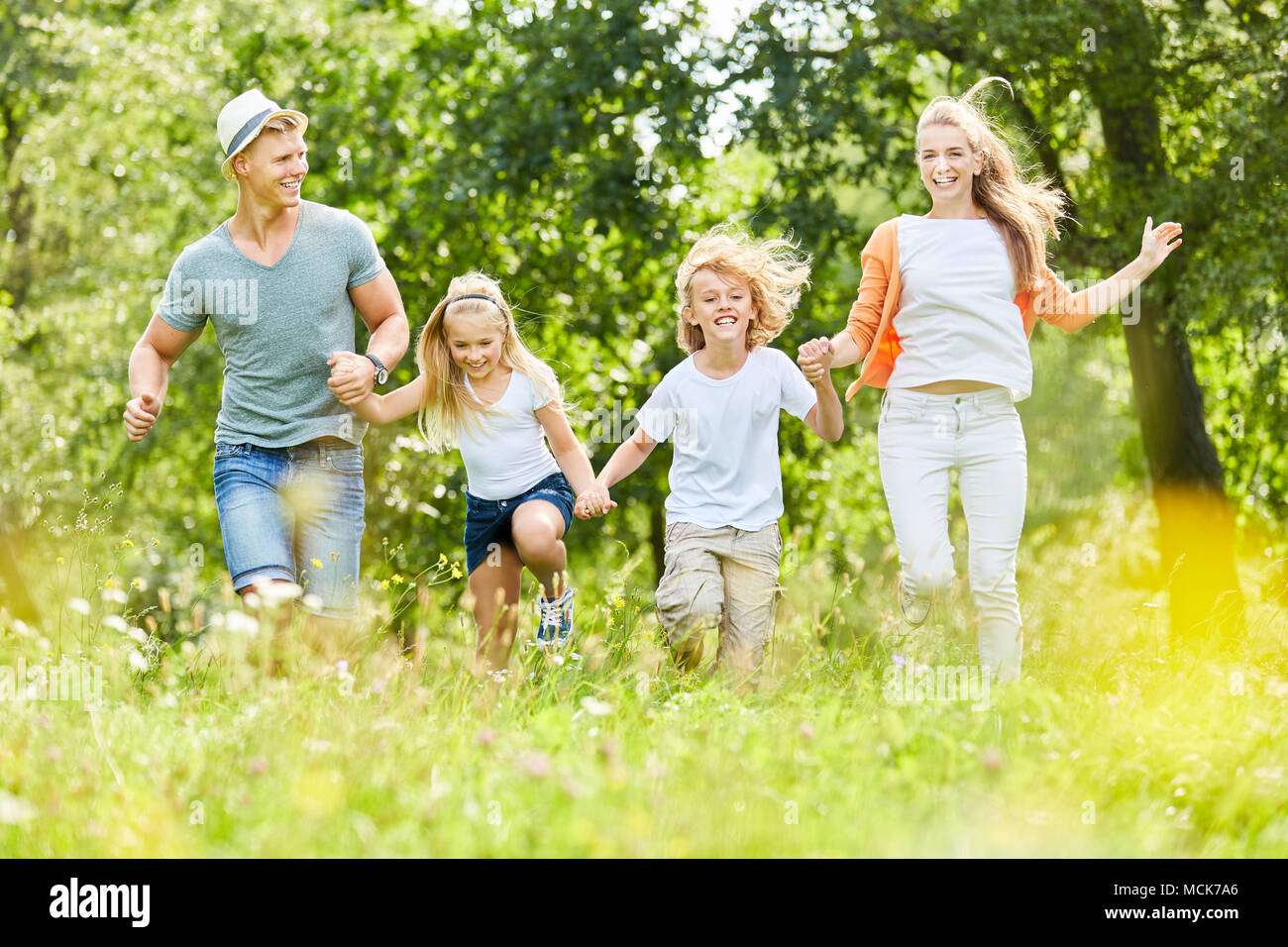 Happy family and kids run over a meadow in spring Stock Photo