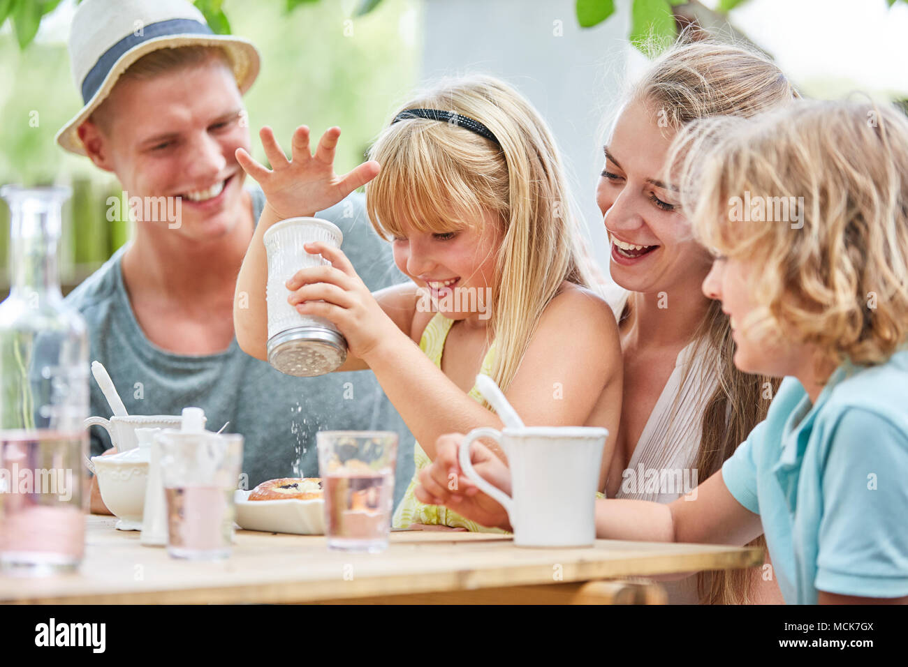 Blond girl is playing with the sugar shaker at the coffee table in the garden Stock Photo
