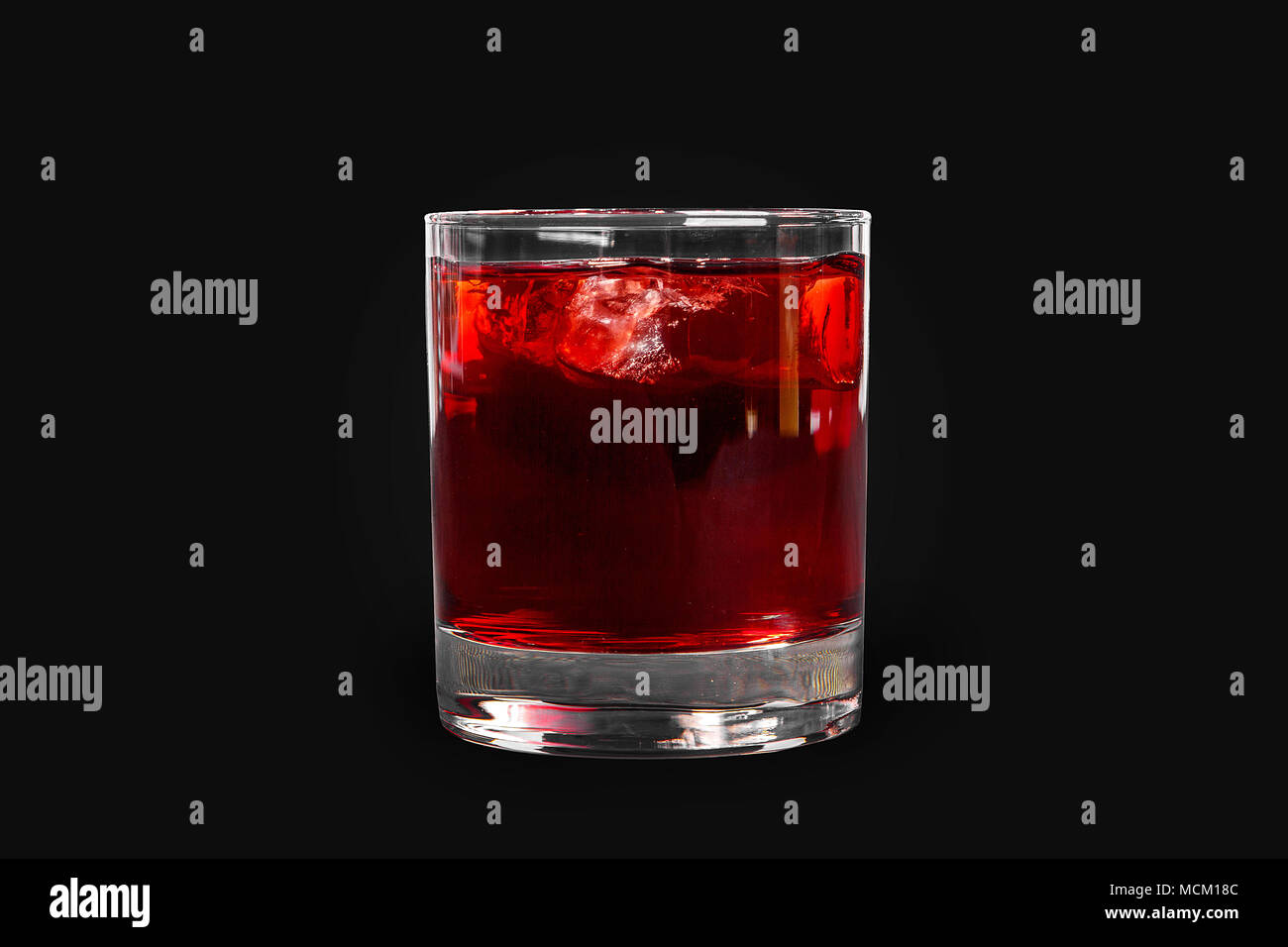 Single-color transparent cocktail, refreshing in a low glass with ice cubes with taste of berries, cherries, strawberries, grapefruit. Side view Isola Stock Photo
