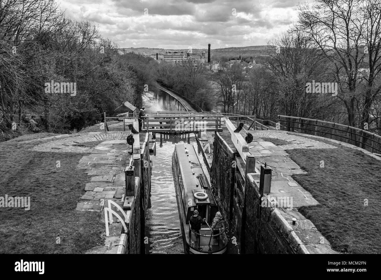 A boat being lowered down The Five Rise Locks on the Leeds and Liverpool Canal,  Bingley, near Bradford, West Yorkshire, England. Stock Photo