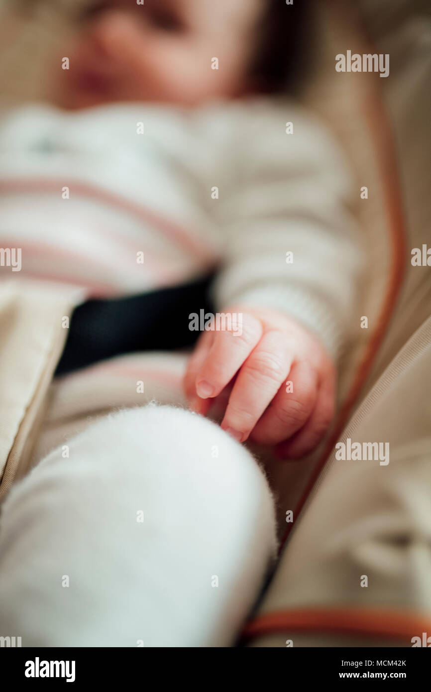 Close up shot of a babies hand while she is sleeping in her bouncer chair. Stock Photo