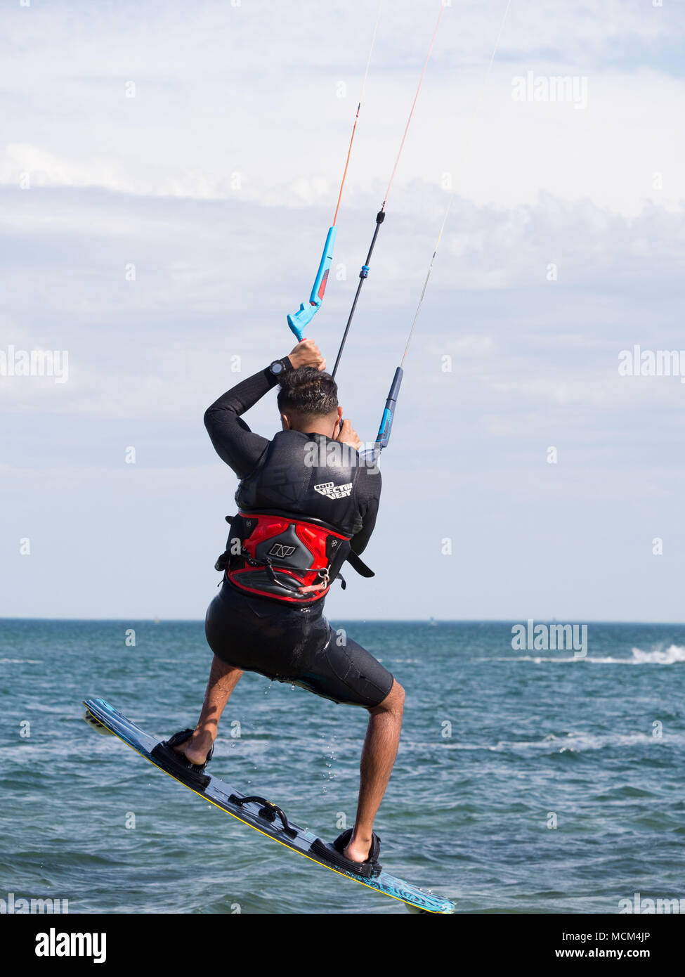 Kiteboarders and kitesurfers on Port Phillip Bay Australia speeding across water, doing tricks, flying in the air on a warm sunny blue sky day Stock Photo