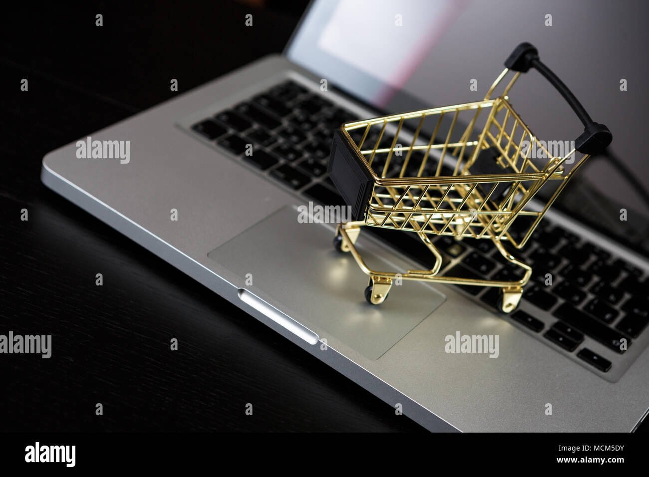 Online shopping bank card nearby a laptop and mini shopping cart Stock