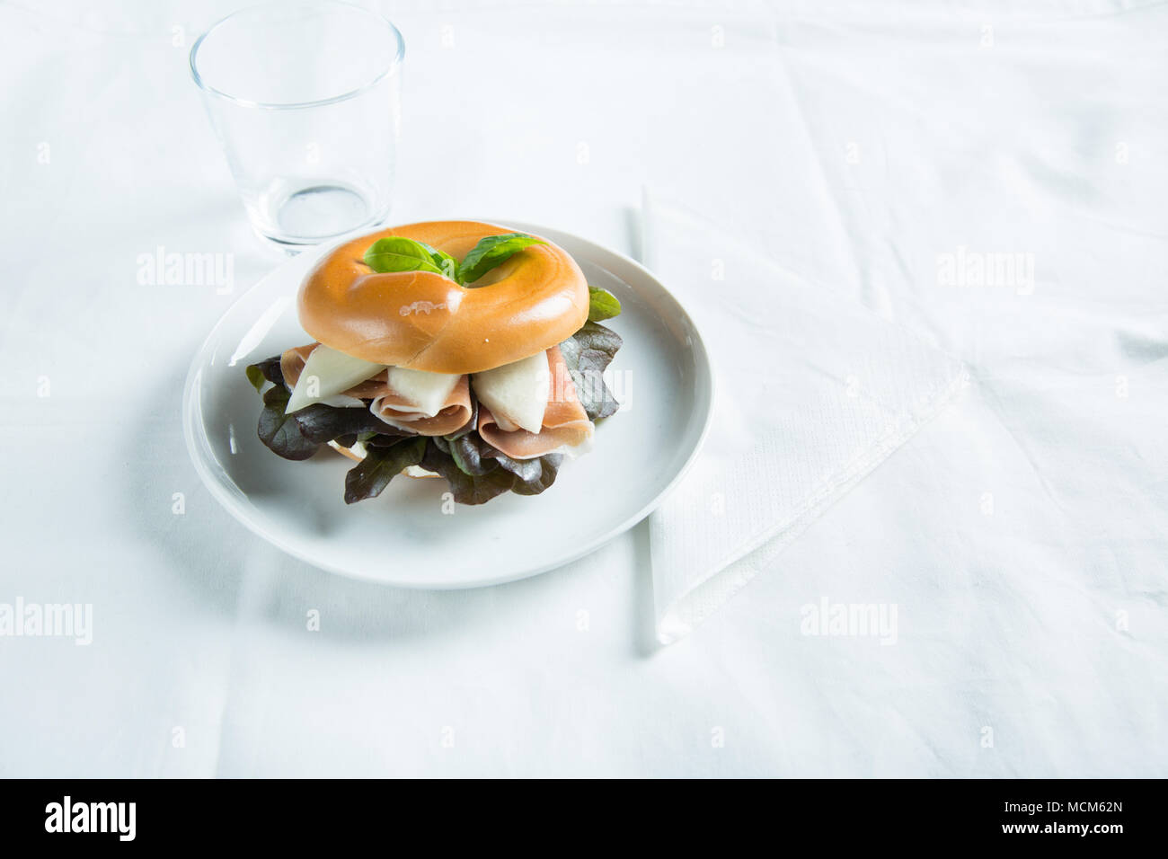 Bagel filled with ham, salad and some fruit. Stock Photo