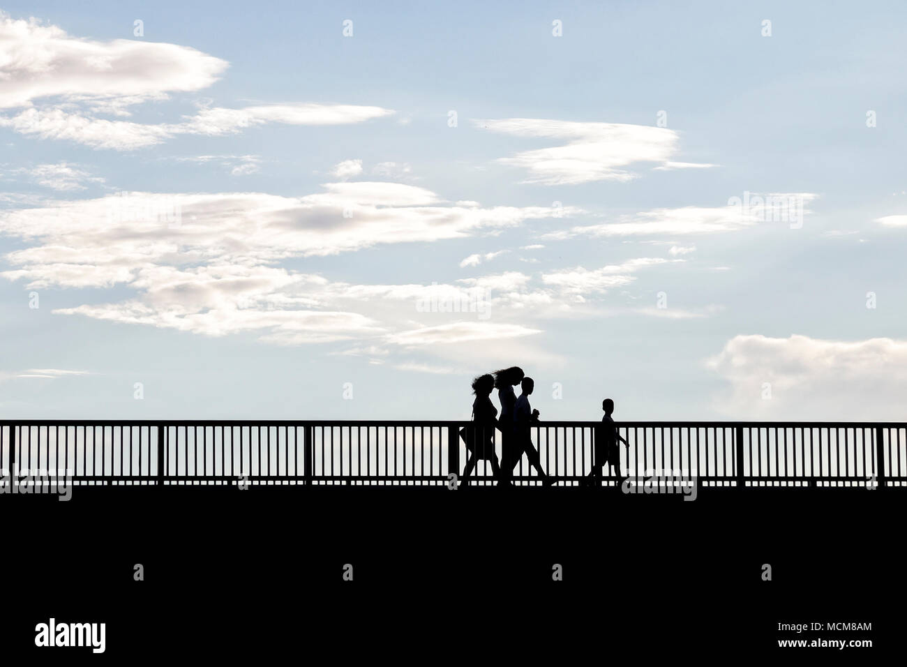 Silhouette of people walking across the bridge Stock Photo