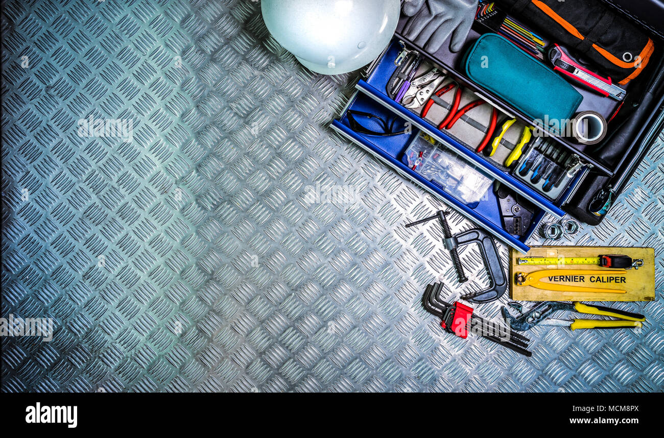 Top view of tools box and helmet on checkered plate background in workshop. Service tools set. Home building and electrical tools. Plumber hand tools. Stock Photo