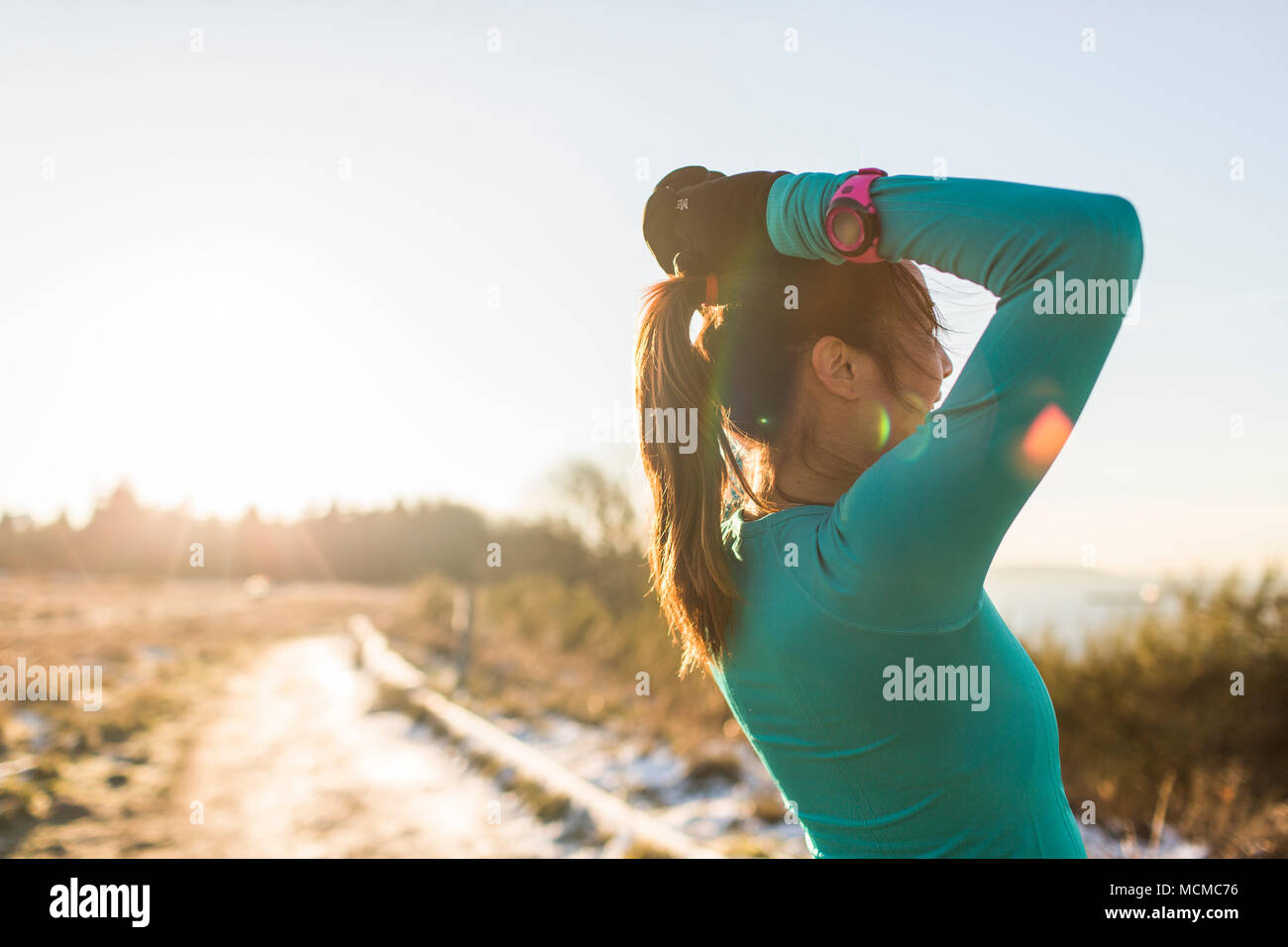 Female runner resting with hands behind head, Discovery Park, Seattle, Washington State, USA Stock Photo