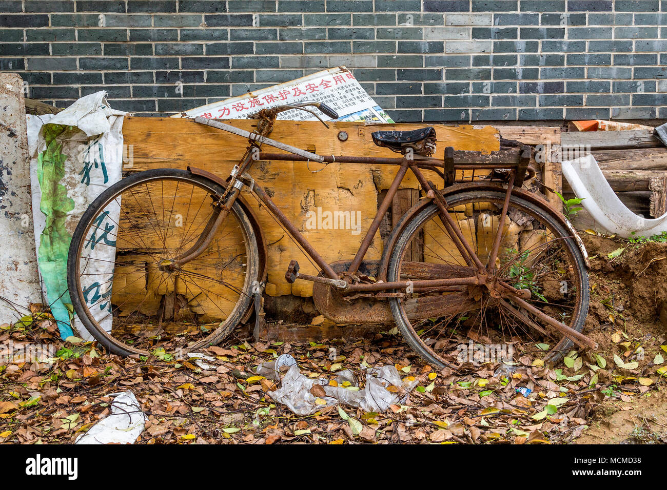 An old, rust-covered bicycle stands forgotten amongst debris and decay. Stock Photo