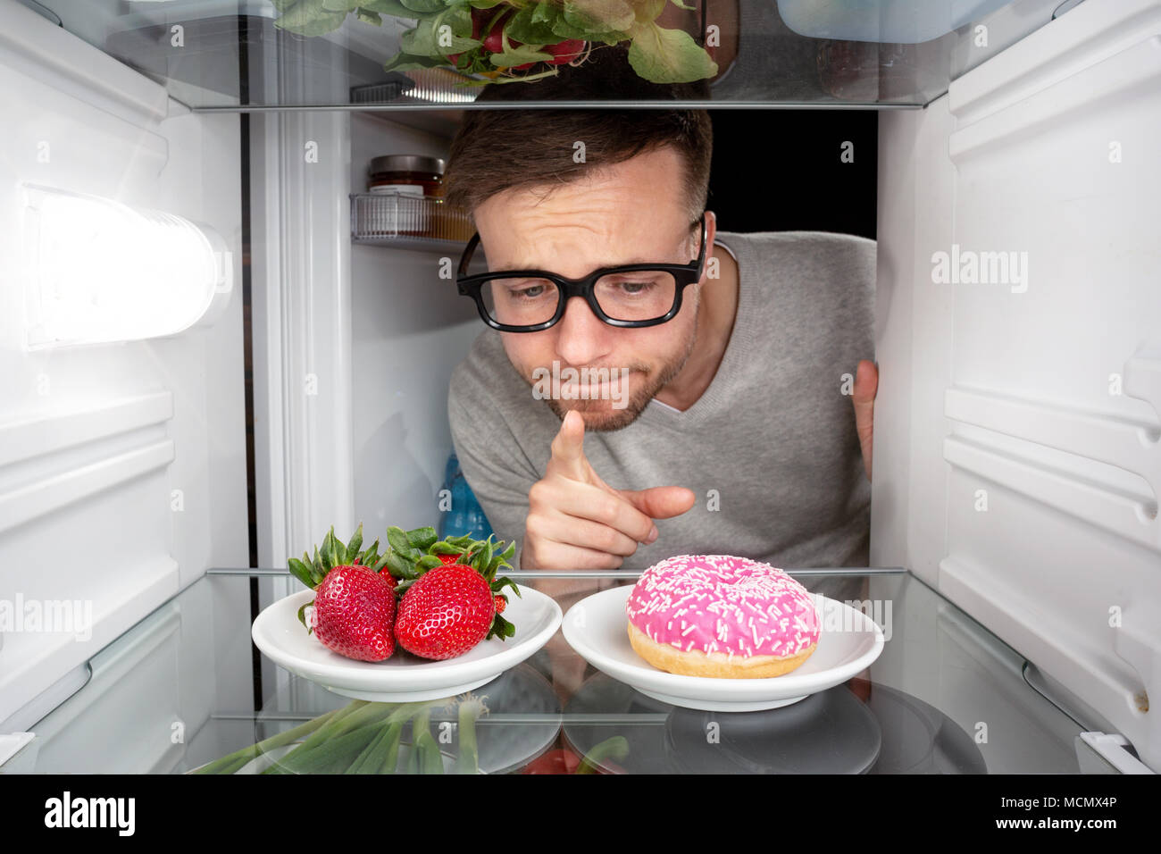 Man choosing between fruits and candy Stock Photo