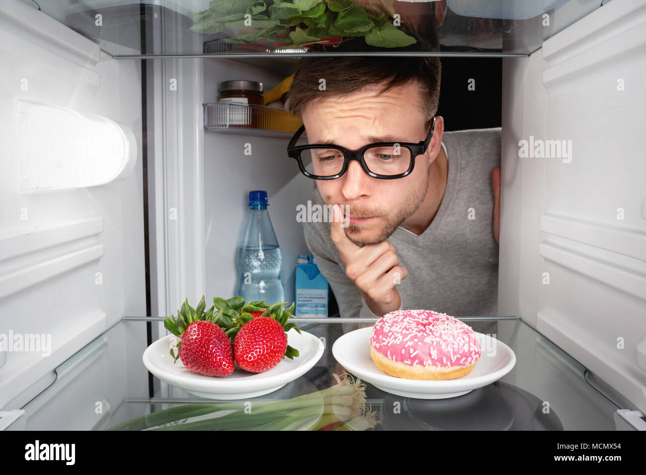 Man choosing between fruits and candy Stock Photo