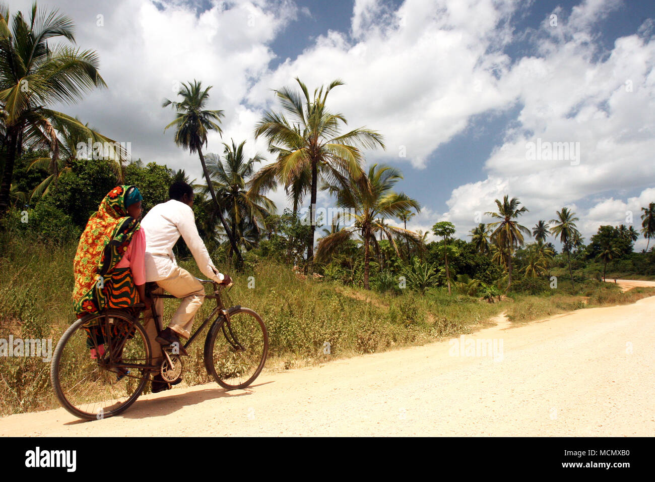A couple riding their bicycle along a dusty road, Dar es Alaam, Tanzania Stock Photo