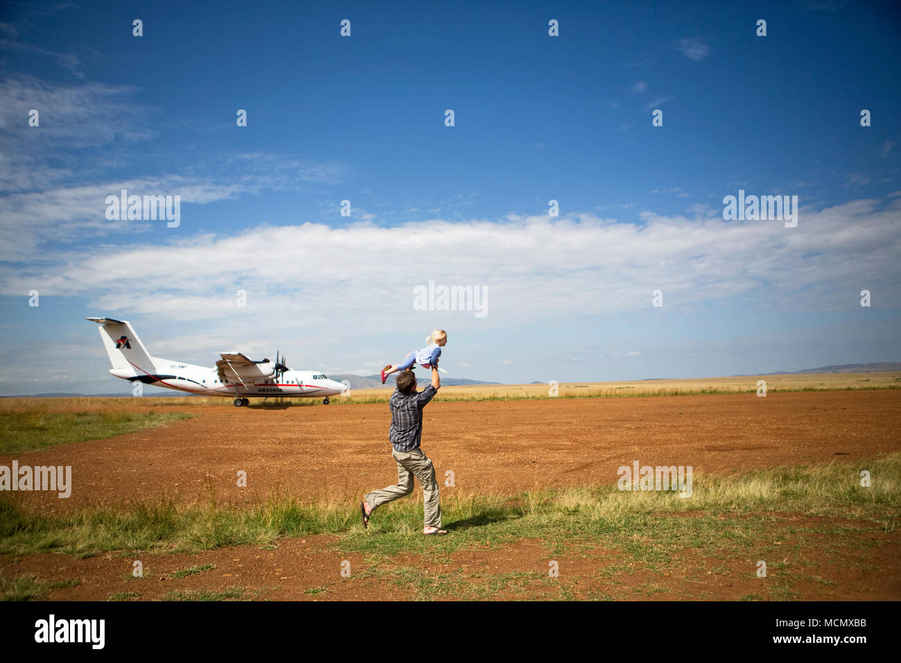 A father and his daughter play on the rustic runway in the Masai Mara, Kenya Stock Photo