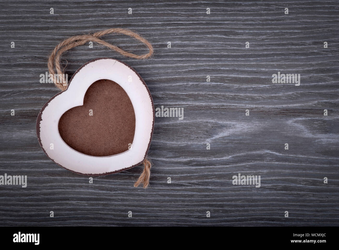 Photo frame in wood heart shape on grey oak wood background. Stock Photo