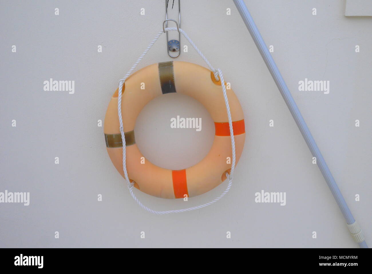 Life ring and pool rescue reach pole hanging on a wall, Bahrain Stock Photo