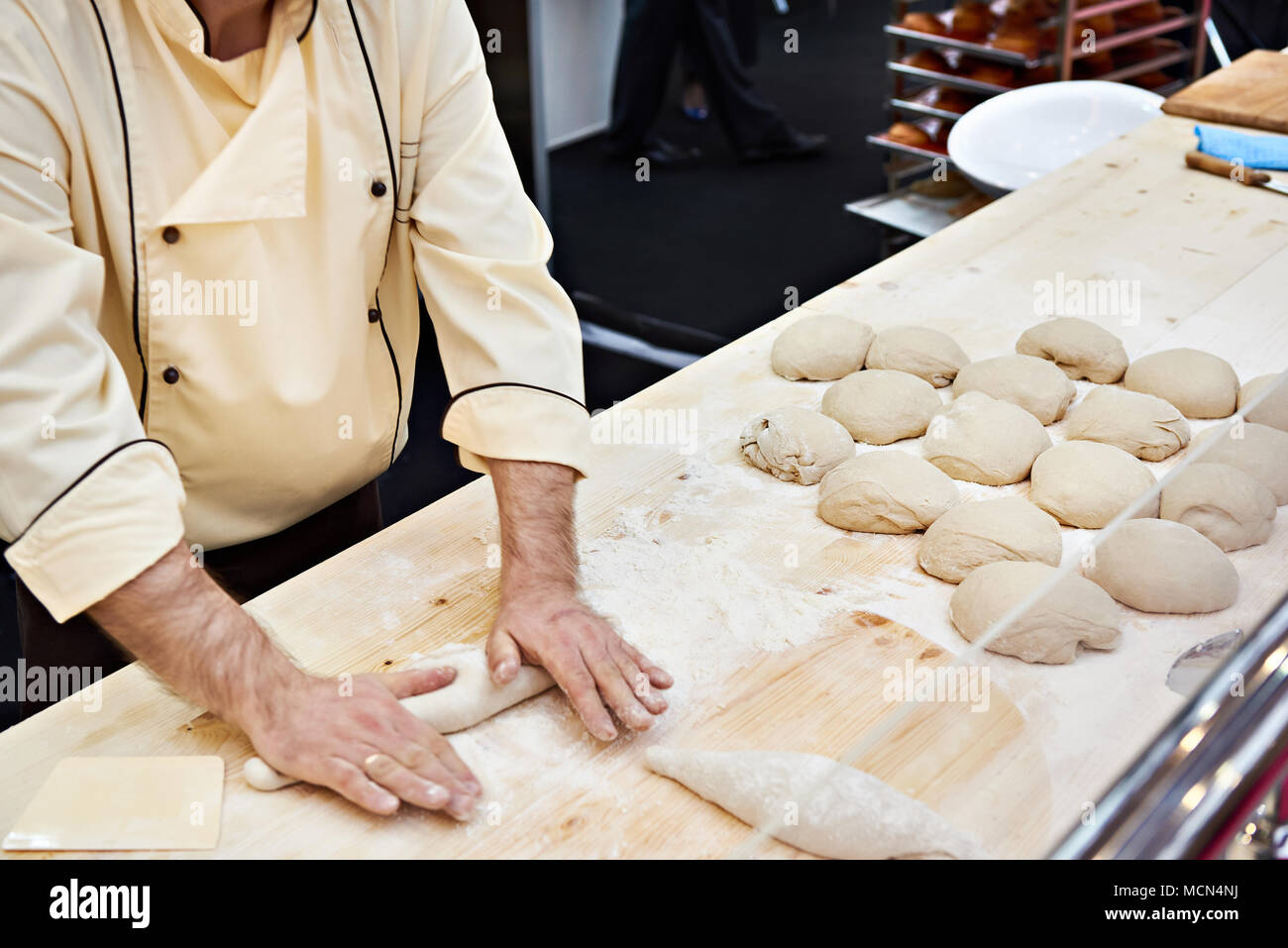 Confectioner baker cook dough for buns on bakery table Stock Photo