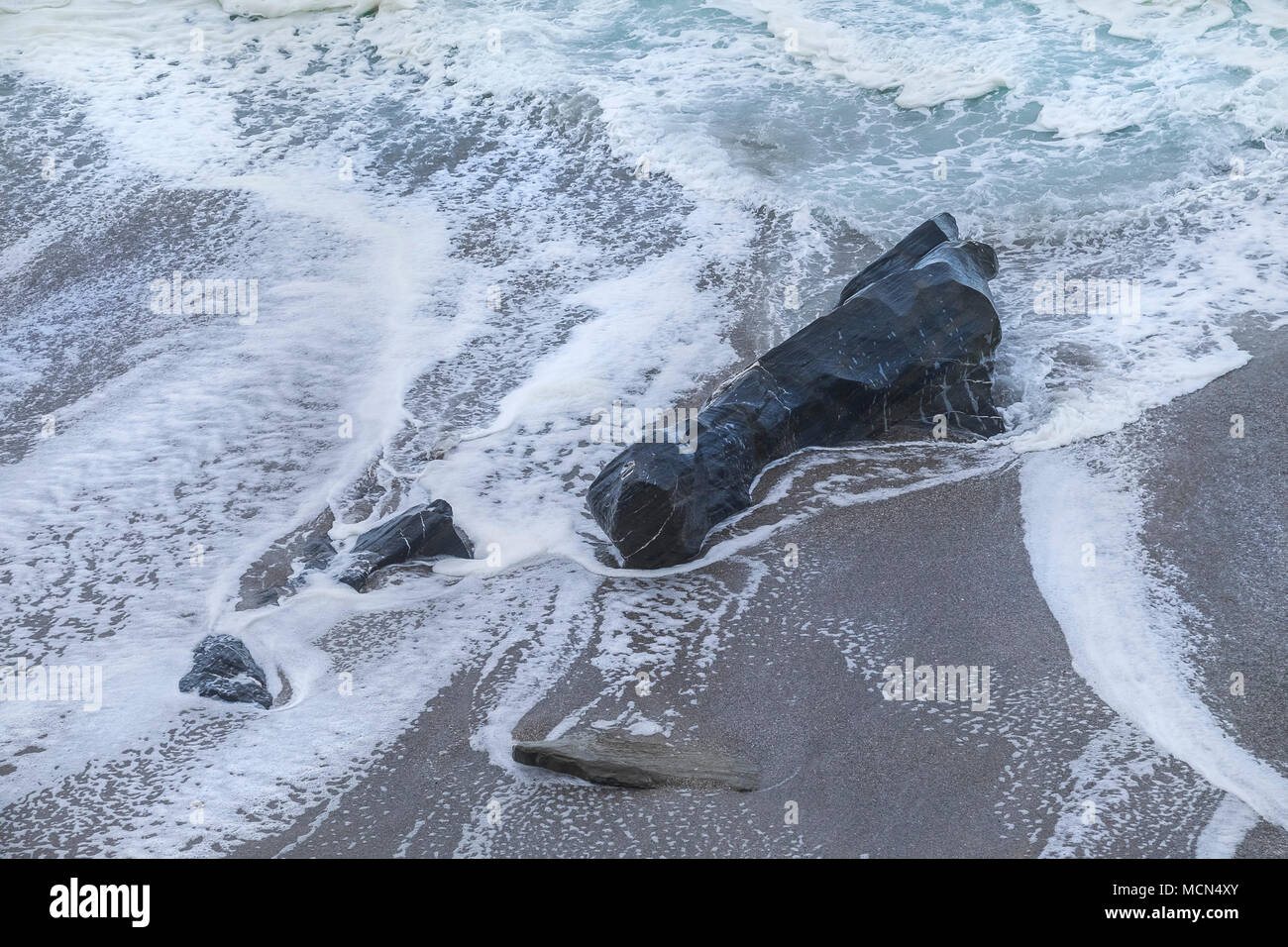 The sea flowing around a rock on the beach at Little Fistral in Newquay Cornwall. Stock Photo