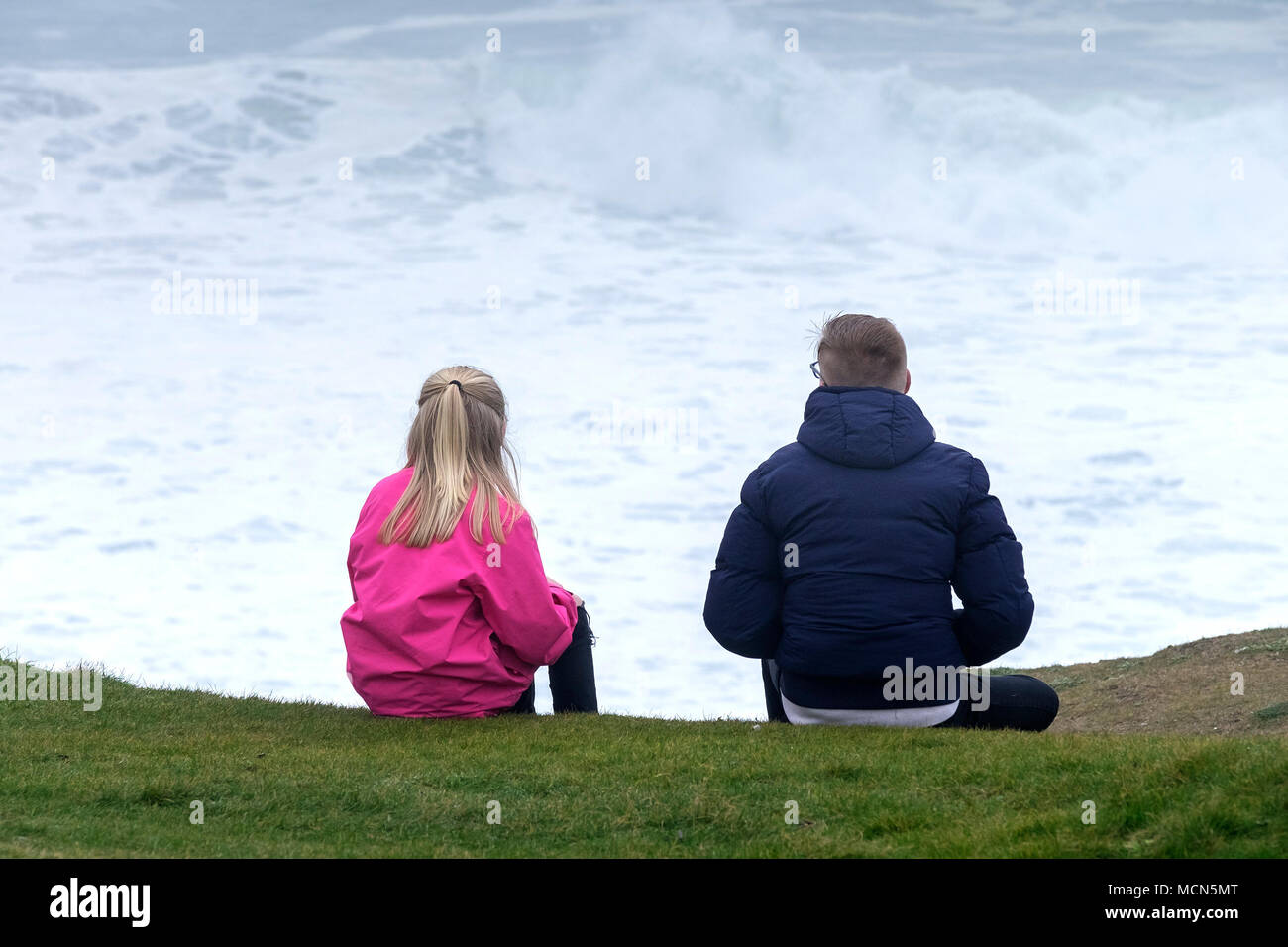 People sitting on the coast overlooking a stormy sea. Stock Photo