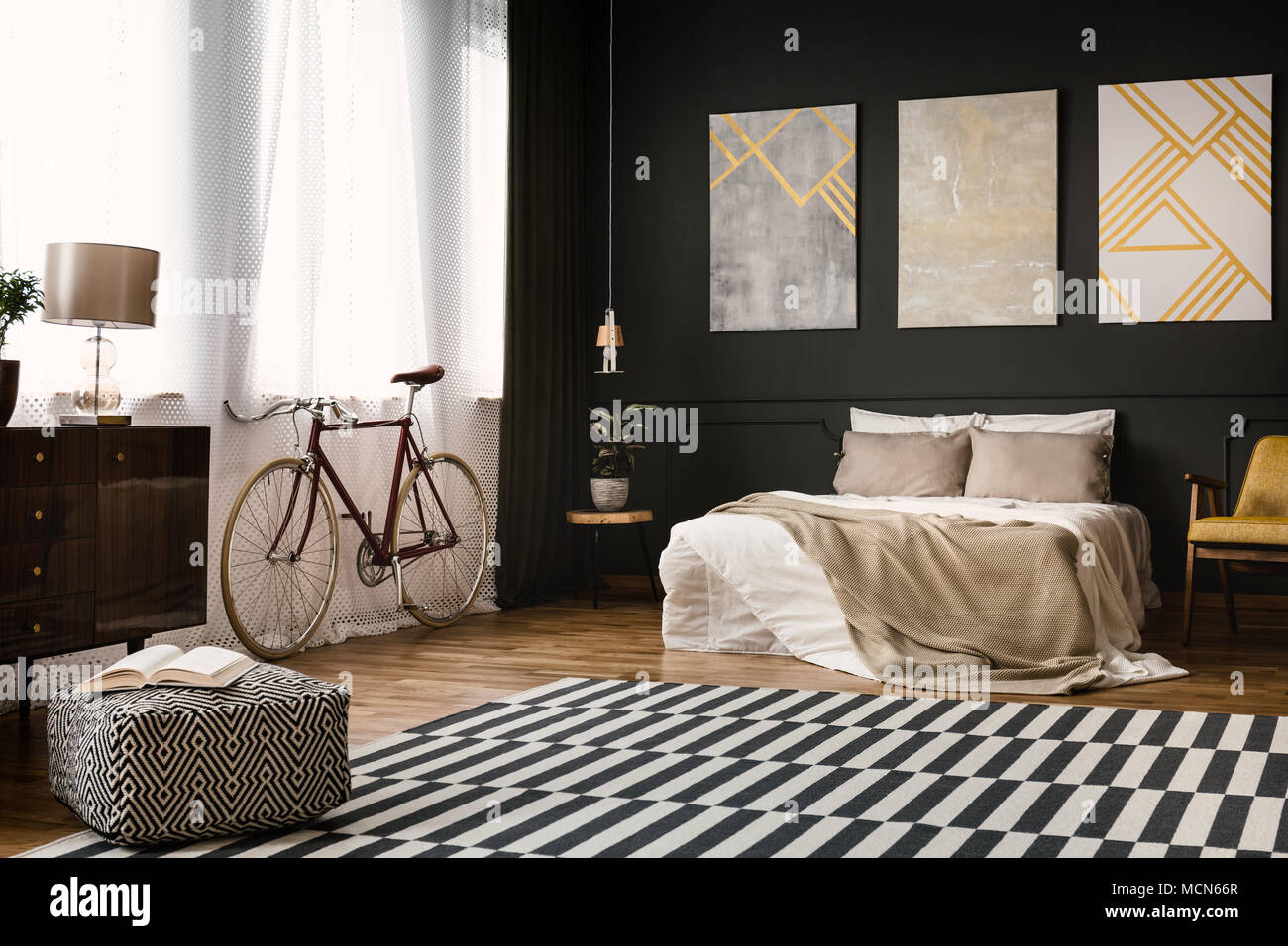 Vintage room interior with bed, bike, carpet on the floor and pouf Stock Photo