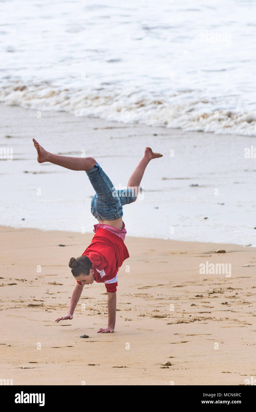 A teenage girl performing a one handed handstand on Fistral Beach in Newquay Cornwall. Stock Photo