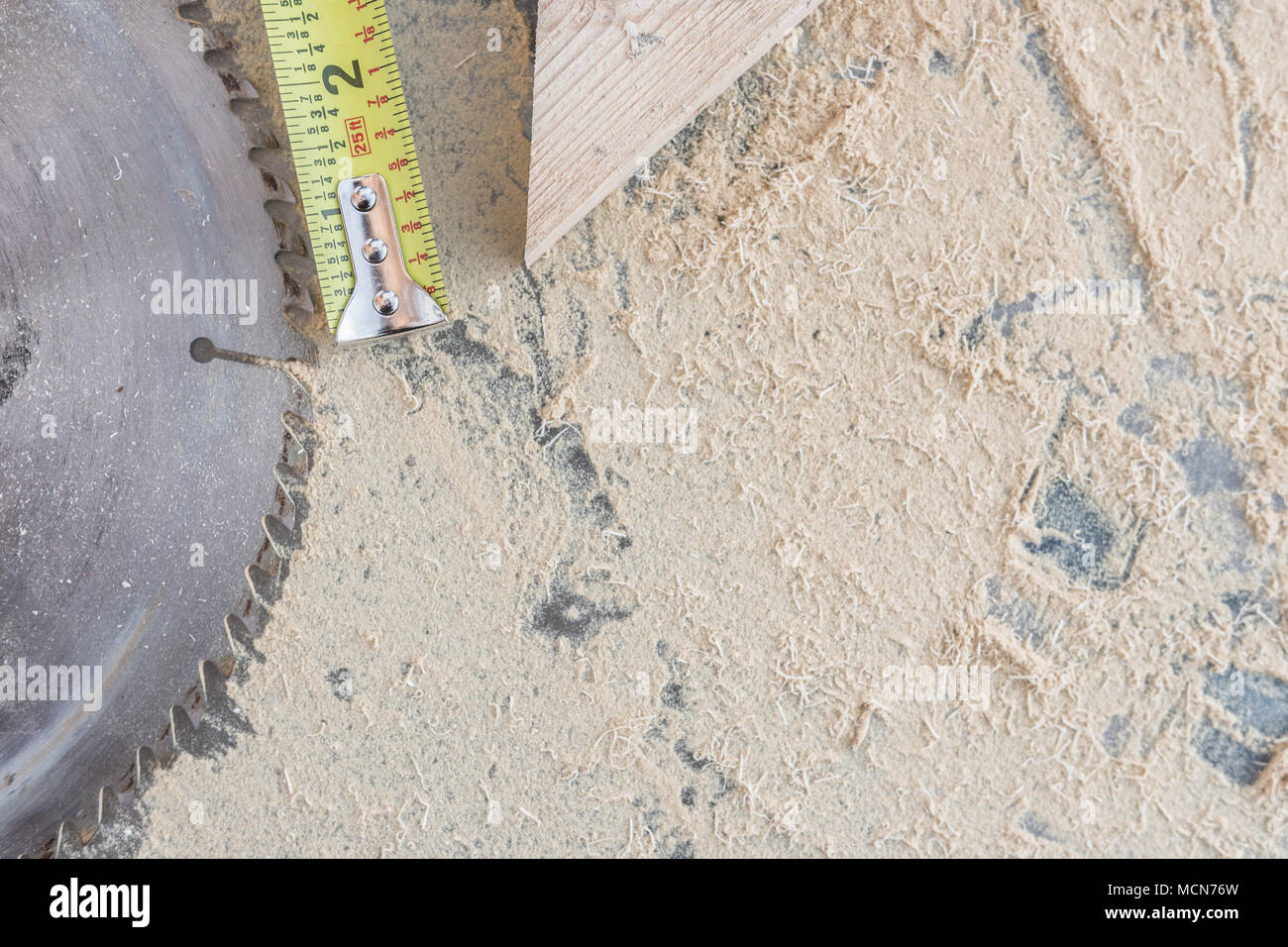 Overhead of shop table; sawdust, tape measure, wood block, saw blade