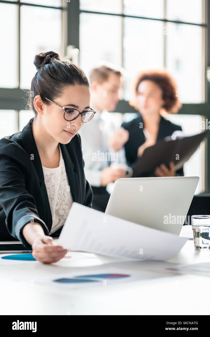 Two young malicious employees gossiping about their colleague Stock Photo