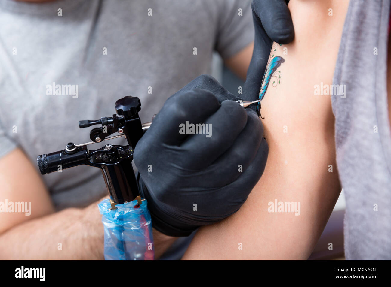Hands of a cautious artist wrapping with dry plastic a new colorful tattoo Stock Photo