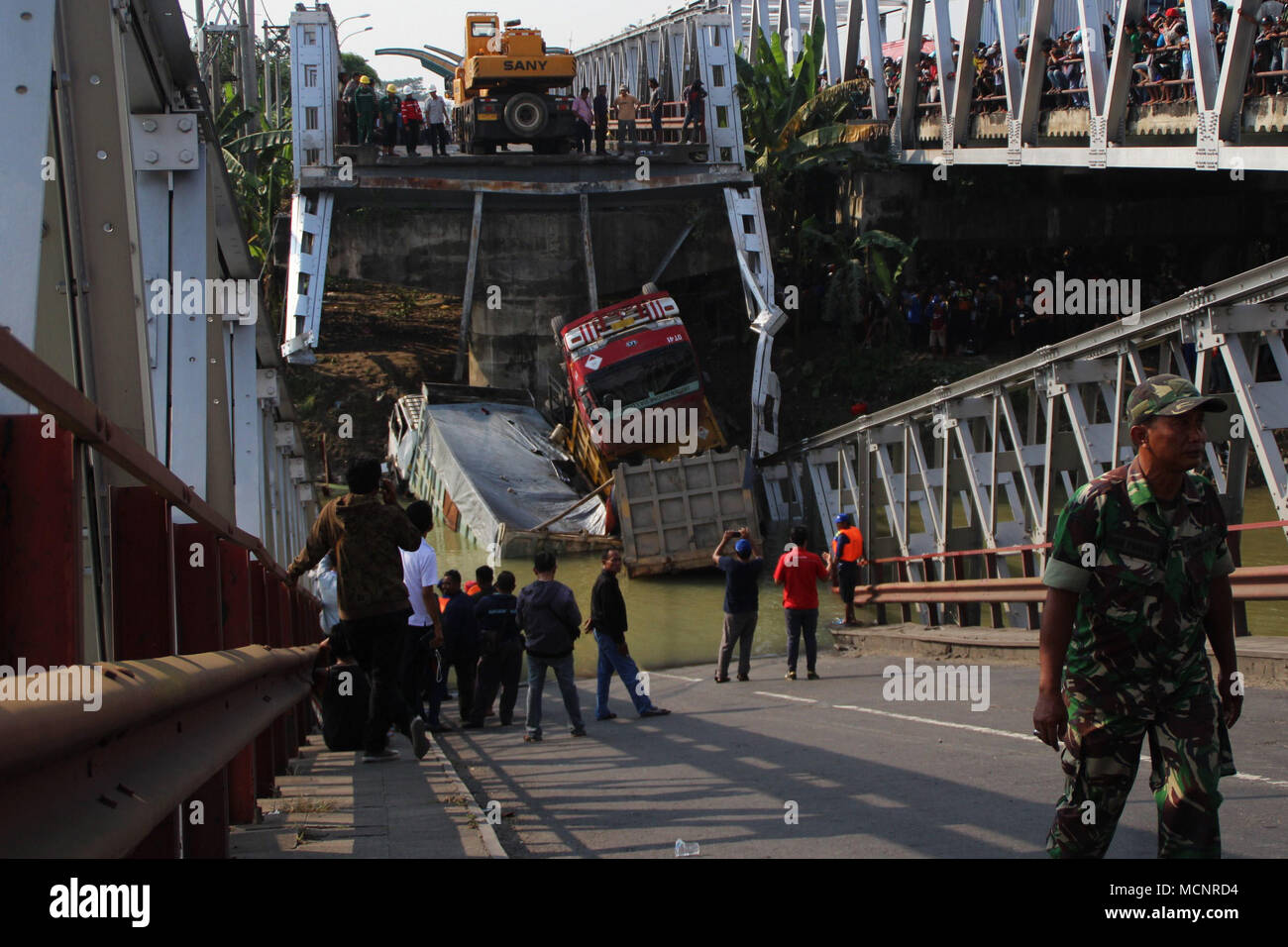 Tuban, Indonesia. 17th Apr, 2018. People watch three trucks and one motorcycle which plunged into the river when the bridge collapsed in Tuban, East Java province, Indonesia, April 17, 2018. Rescuers discovered two corpses of truck drivers and are searching for other missing people after a bridge fell down in East Java province of Indonesia on Tuesday, a disaster agency official disclosed. Credit: Kurniawan/Xinhua/Alamy Live News Stock Photo