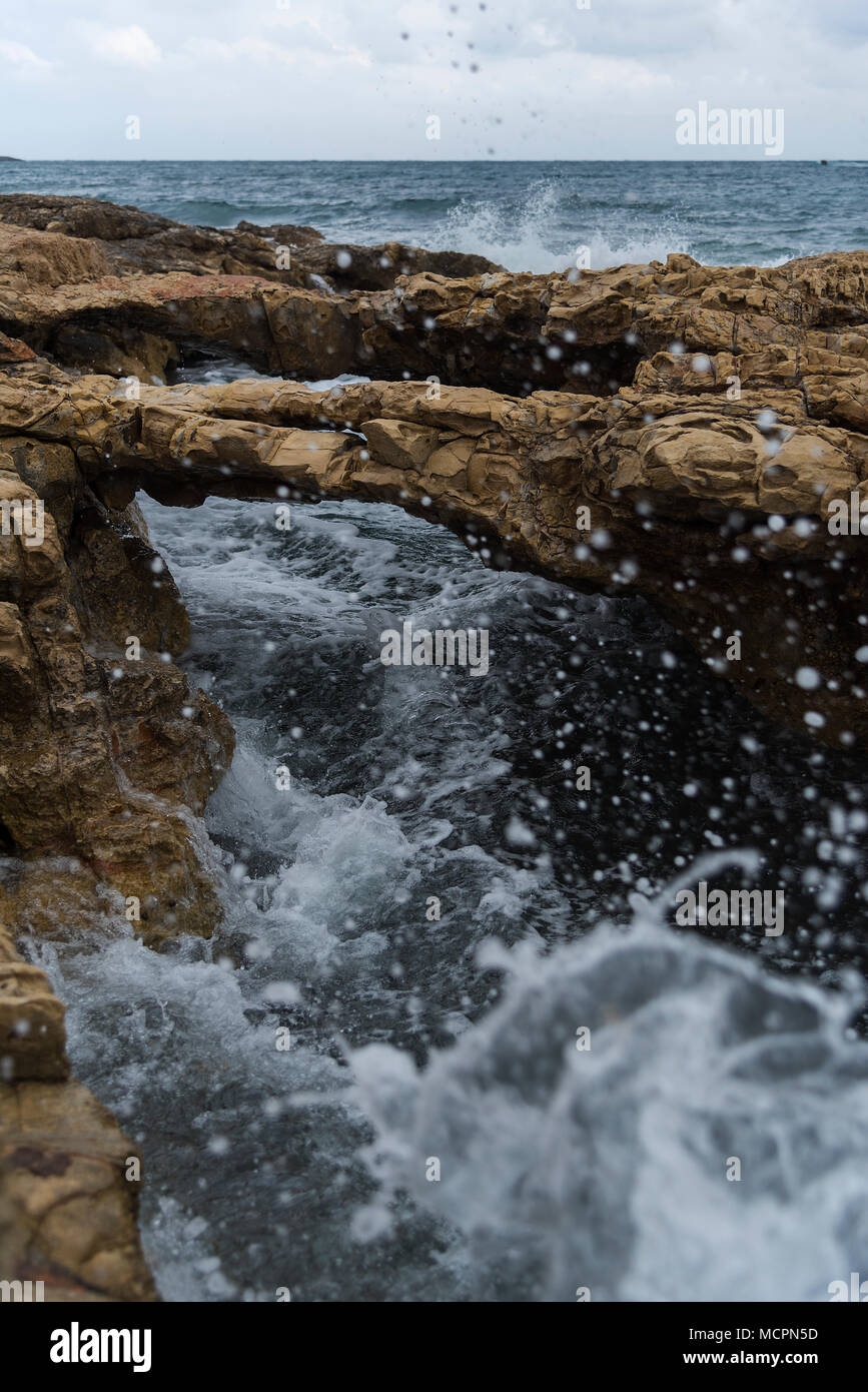 Unter Felsenbrücken an der Küste von Chersonissos schiesst tosend das Meerwasser Stock Photo