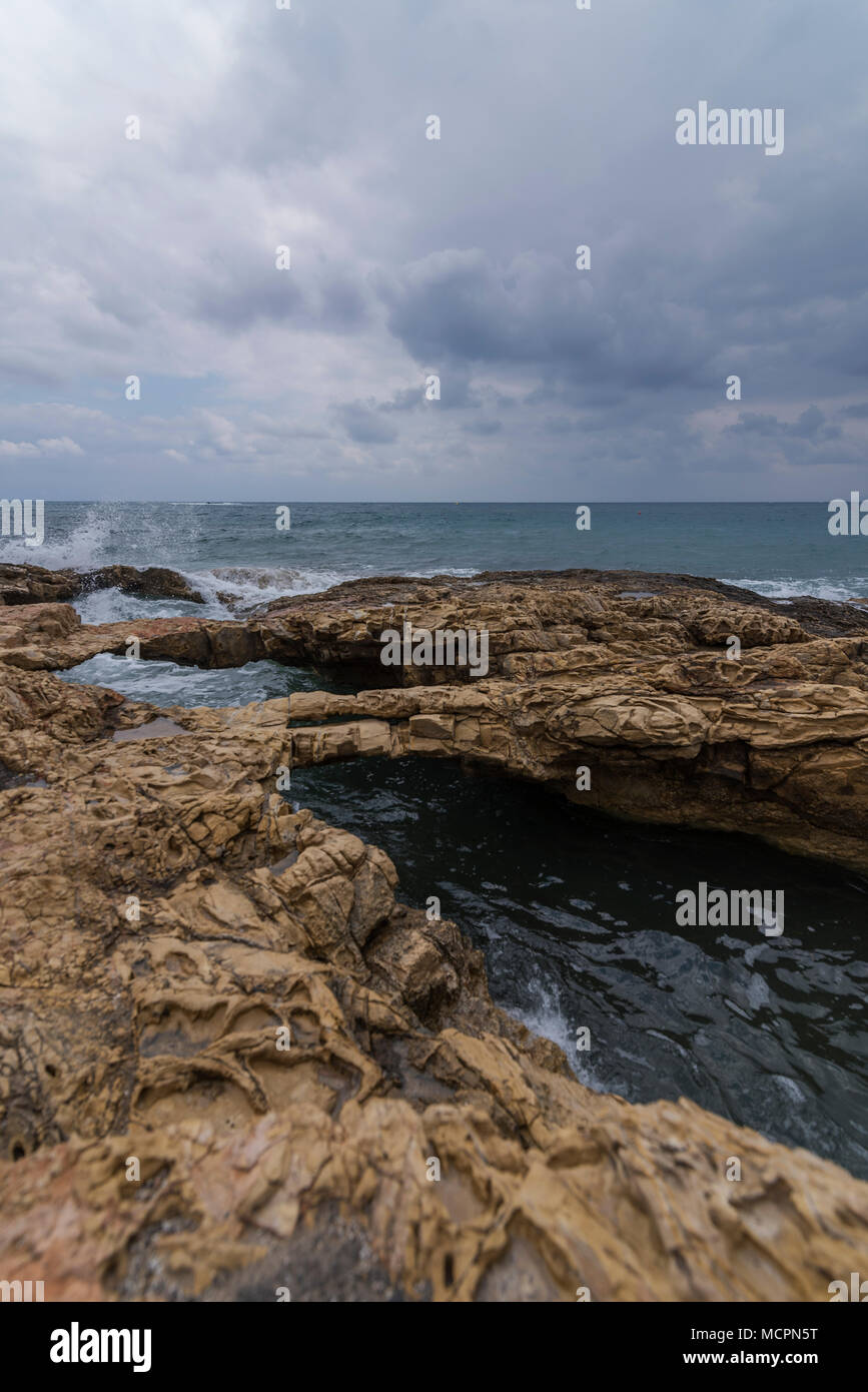 Unter Felsenbrücken an der Küste von Chersonissos schiesst tosend das Meerwasser Stock Photo