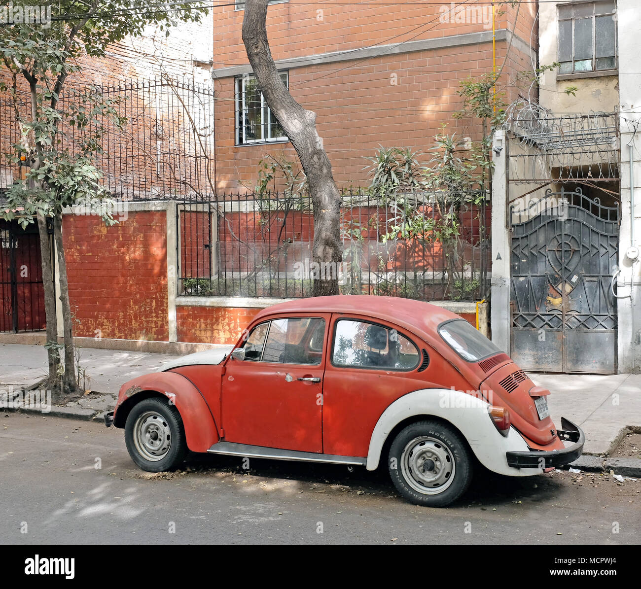 An orange and white Volkswagen Beetle parked outside the beat poets landmark at 210 Orizaba in the La Roma neighborhood of Mexico City. Stock Photo