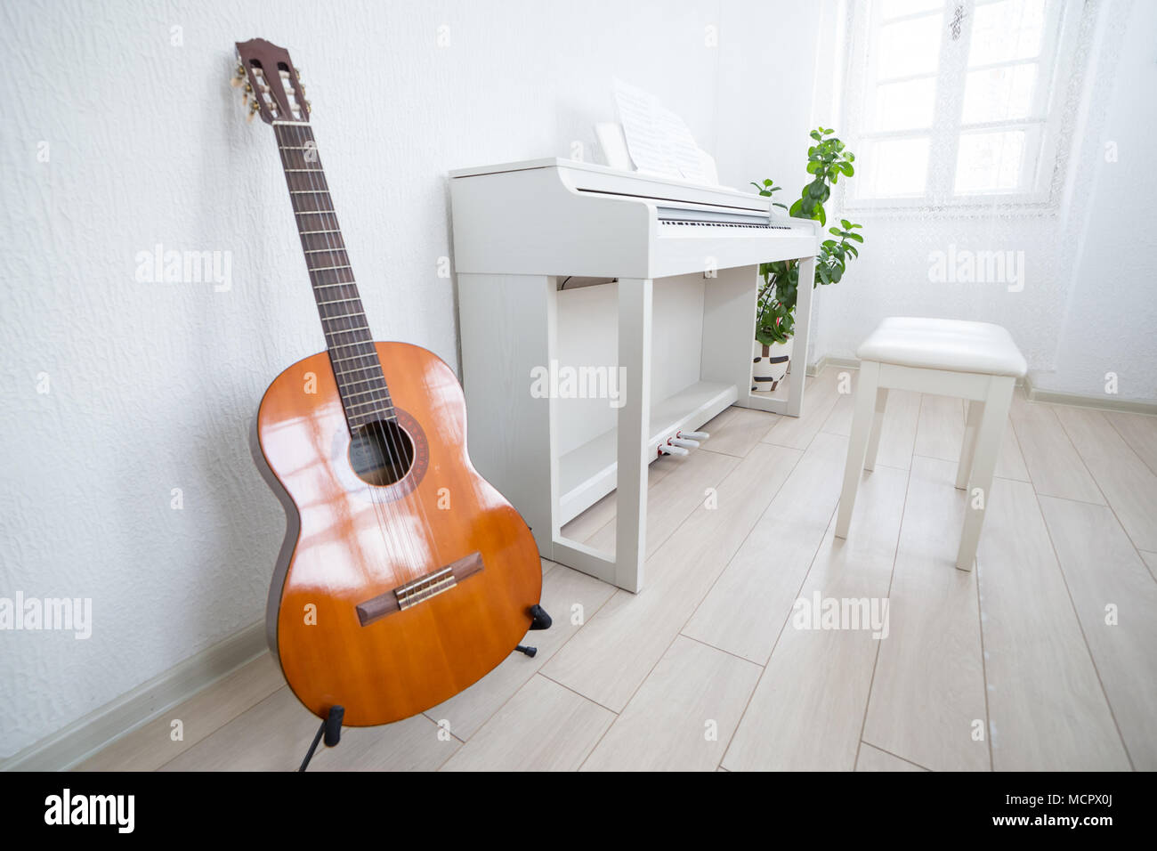 Modern daylight classroom for teaching music. Guitar, white piano and greenboard in modern music classroom Stock Photo