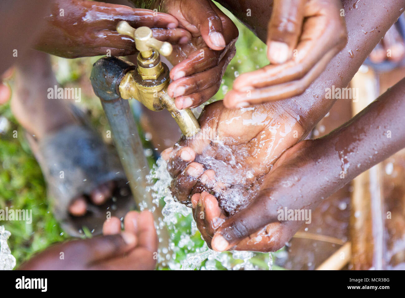 Ugandan children washing their hands at an outdoor water tap Stock