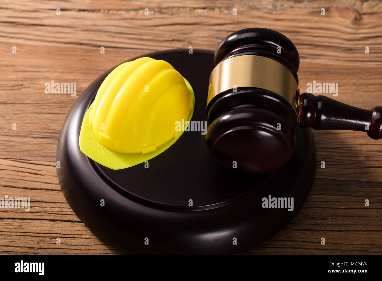 High Angle View Of Yellow Hard Hat And Gavel On Wooden Desk Stock Photo