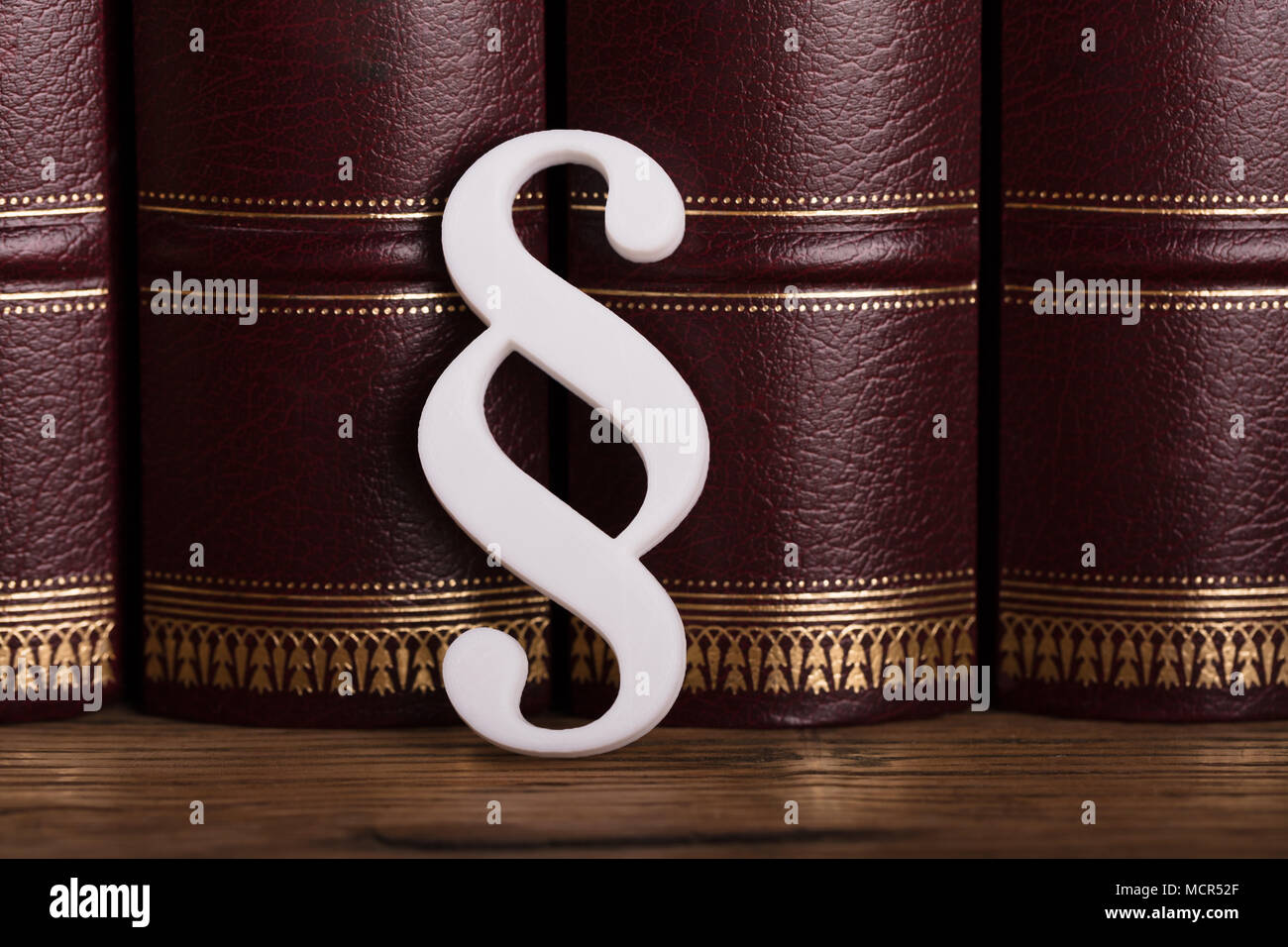Close-up Of White Paragraph Symbol Leaning On Law Books In Courtroom Stock Photo
