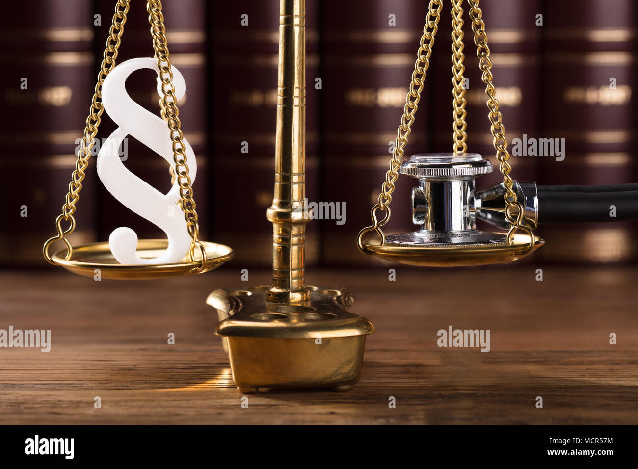Close-up Of White Paragraph Symbol And Stethoscope On Justice Scale In Courtroom Stock Photo