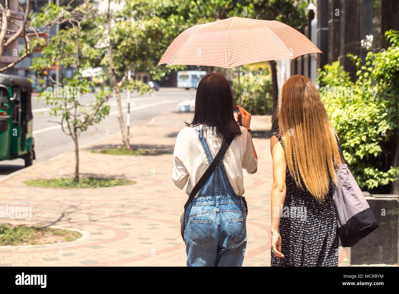 Two girls walking umbrella hi-res stock photography and images - Alamy