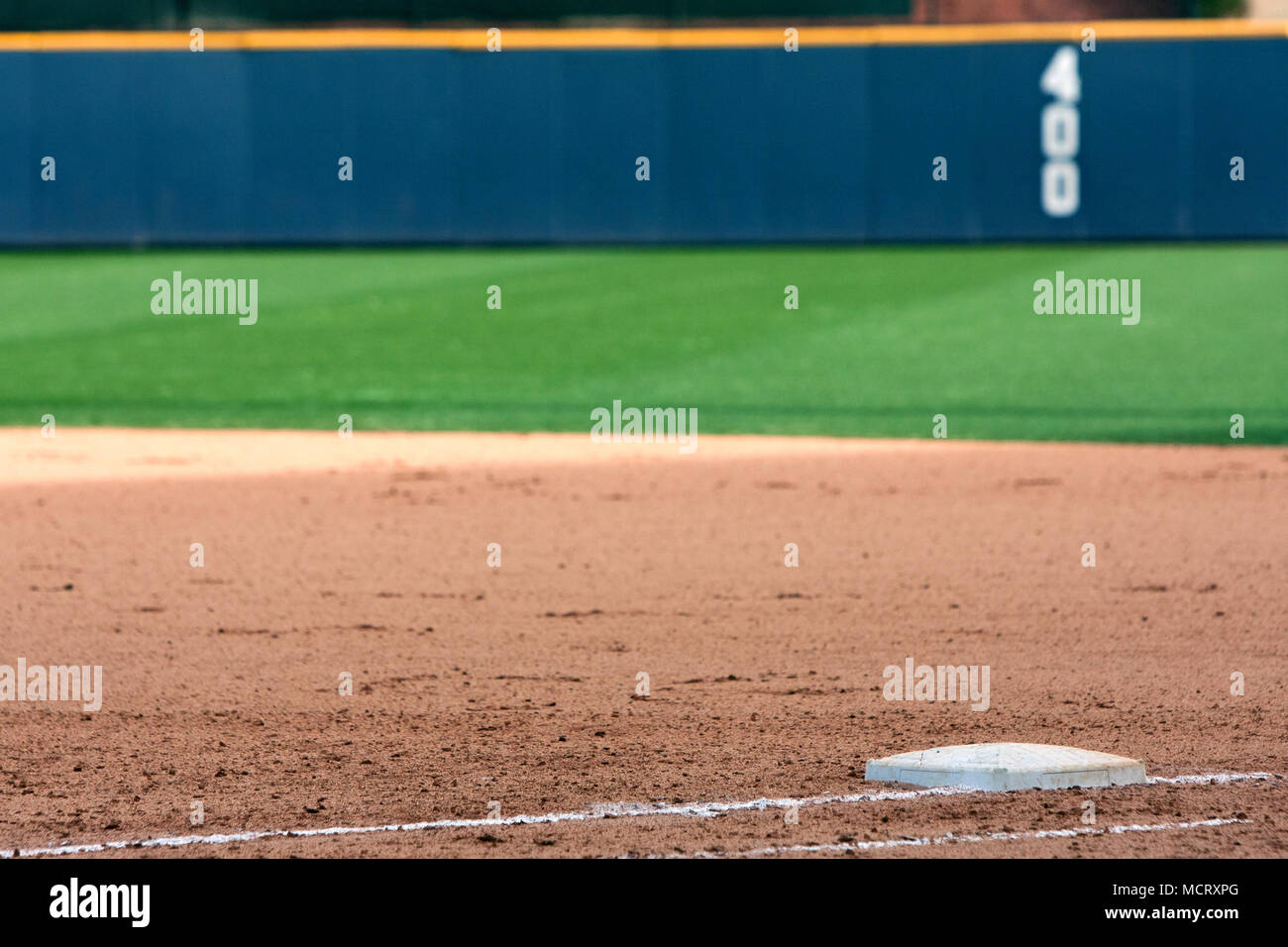 Empty baseball field highlights first base and outfield wall. Stock Photo