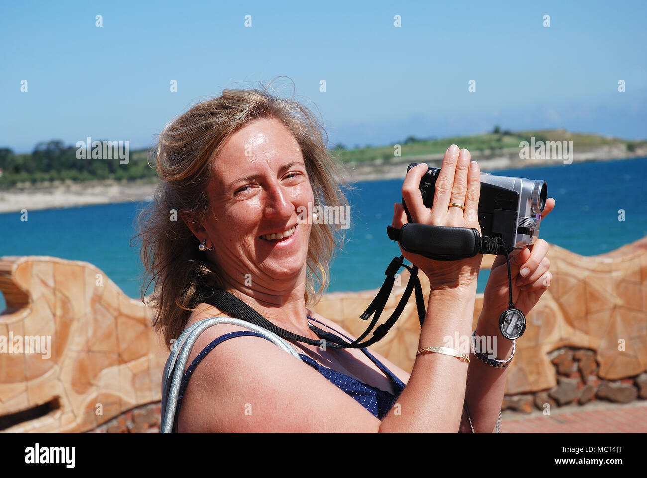 Mature woman with video camera, smiling and looking at the camera. Stock Photo