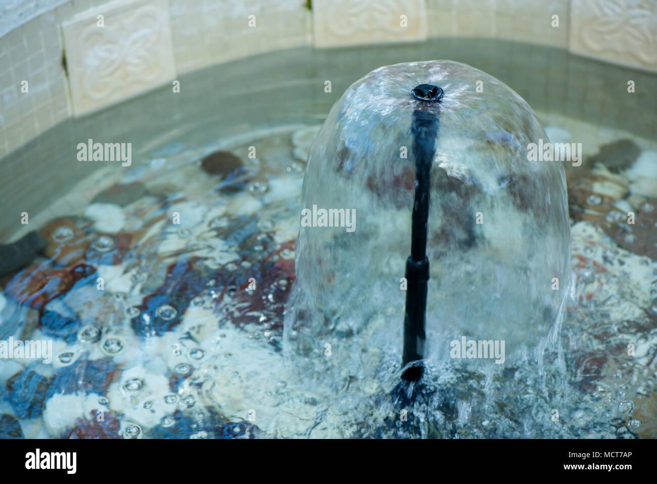 Small indoor fountain in a pool with decorative stones, pebbles and