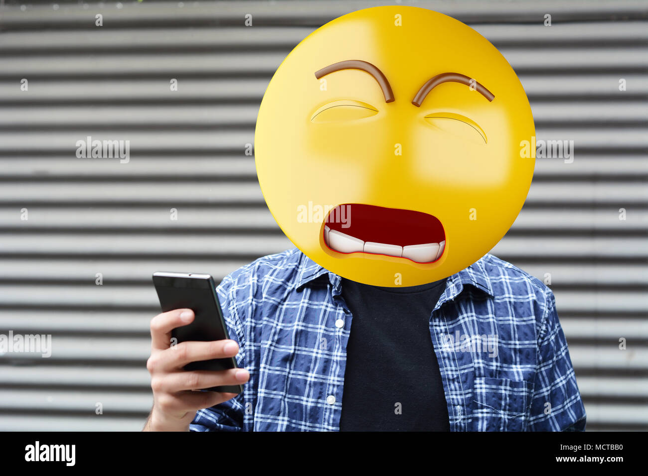 Sad Emoji head man using a smartphone. Emoji concept. Stock Photo