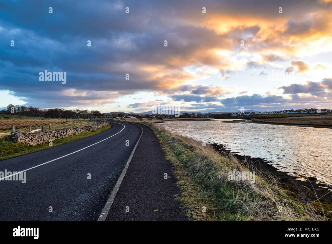 A curving road by a river at sunset Stock Photo