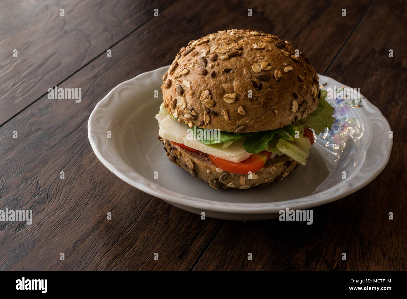 Healthy Sandwich with tomato and cheese in a mixed seeds bread on a wooden surface. Stock Photo