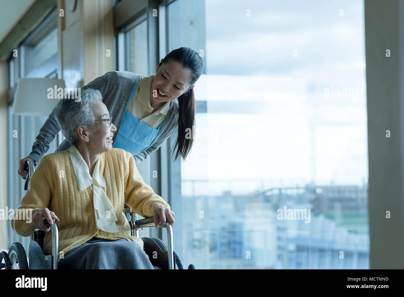 Care worker assisting senior couple in wheelchair Stock Photo