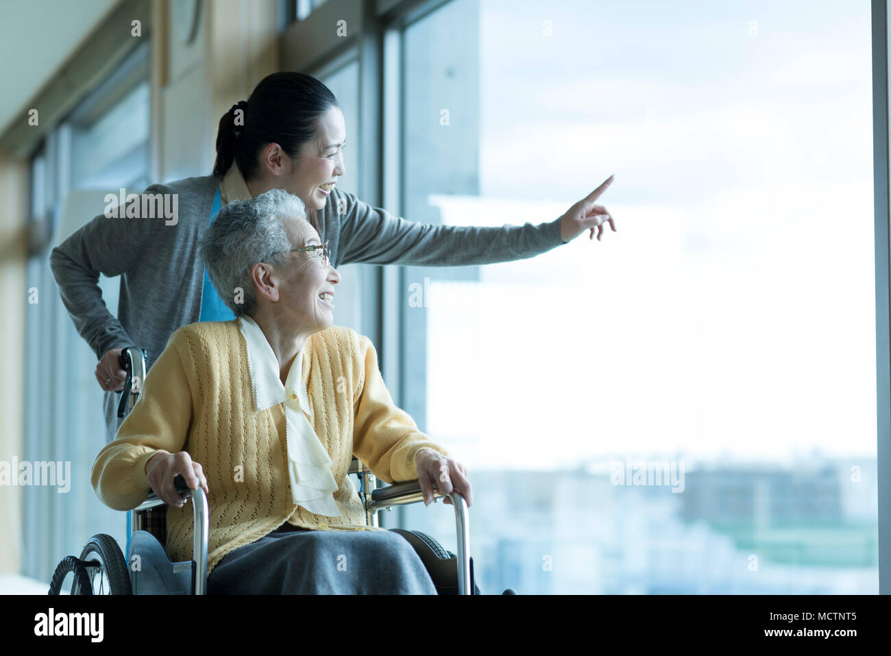 Care worker assisting senior couple in wheelchair Stock Photo