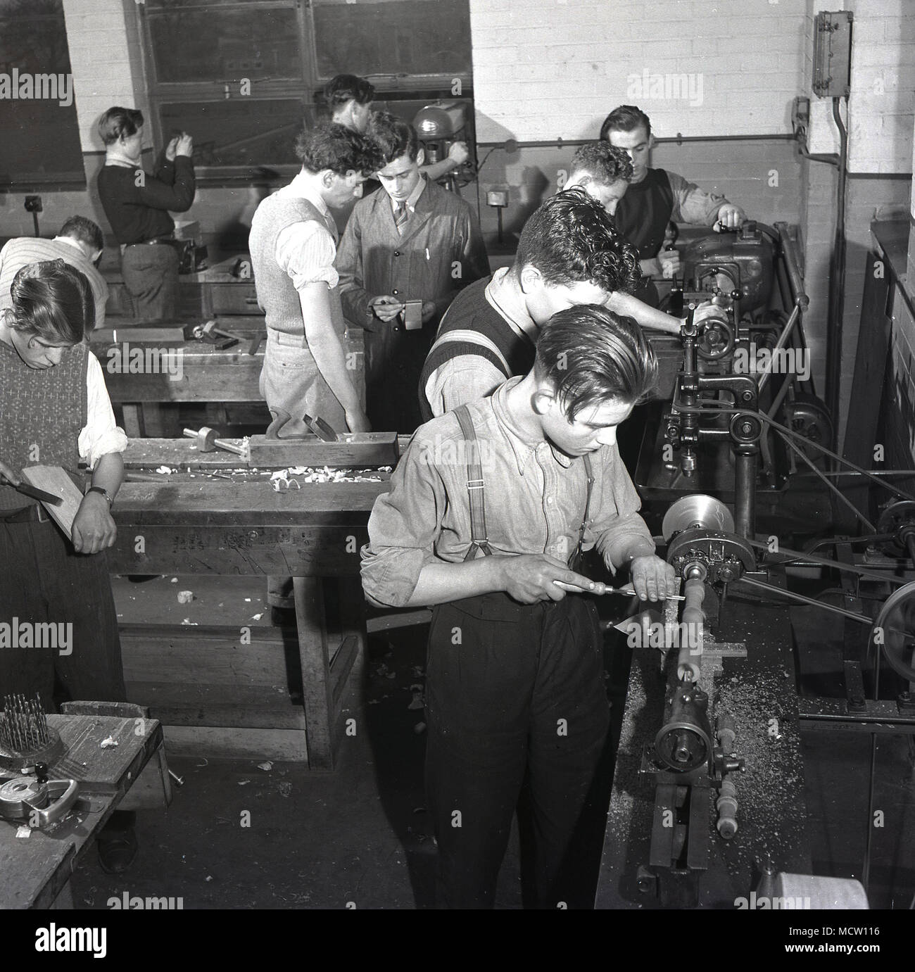 Historical picture, 1950s, of a group of male engineering apprentices using machine tools and getting 'hands on', practical experience in an industrial workshop, England, UK. In post-war Britain there was a major expansion of technical colleges and apprenticeship schemes to encourage more young people into important industrial sectors such as engineering and manufacturing. Stock Photo