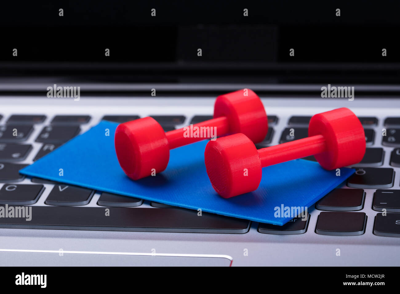 Elevated View Of Dumbbells And Exercise Mat On Computer Keyboard Stock Photo