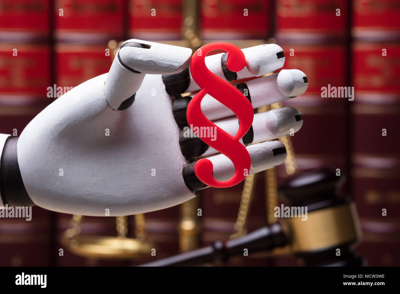 Close-up Of A Robotic Hand Holding Paragraph Symbol In Courtroom Stock Photo
