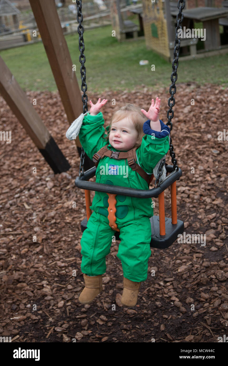Toddler in a baby swing at the park in winter, UK Stock Photo Alamy