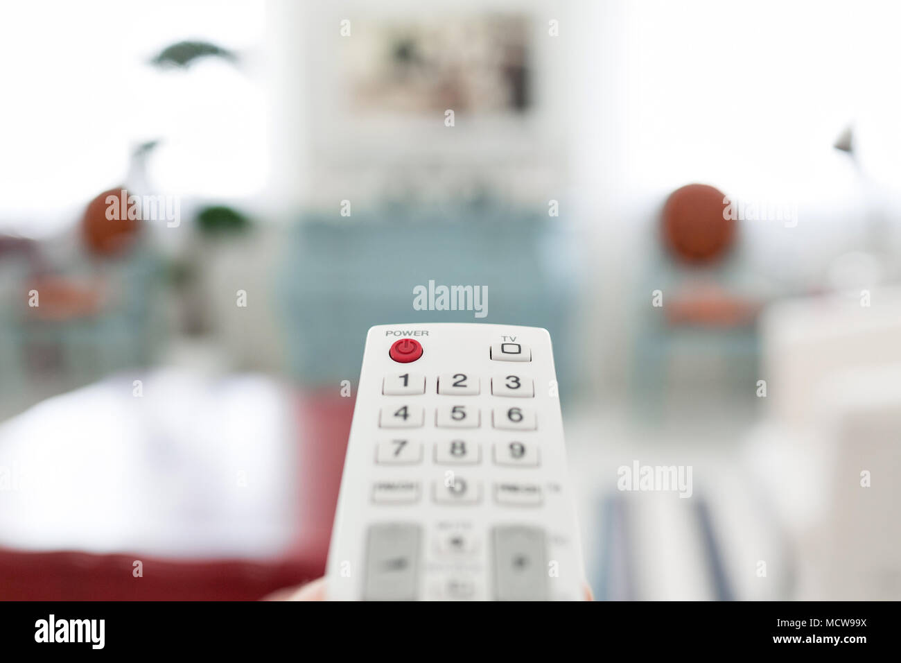 White remote control. Program switching on TV keypad. Bright living ...