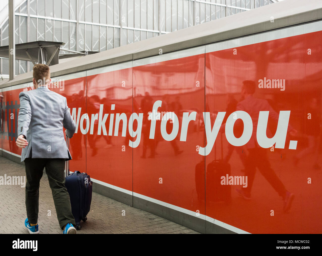 Commuters in front of a Network Rail, Working for You ,advertisement at ...